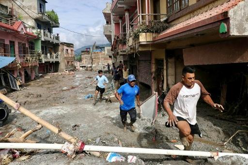 Des habitants passent devant des maisons noyées sous la boue après des crues soudaines à Devighat au Népal, le 27 août 2026 — Prabin RANABHAT / AFP