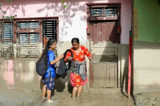 Des femmes devant une maison portant des traces de boue indiquent le niveau de l’eau après des crues dévastatrices près de Devighat, au Népal, le 27 août 2026 — Prabin RANABHAT / AFP