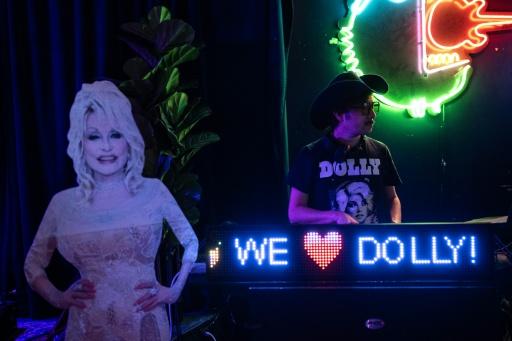 Un DJ joue de la musique à côté d’une silhouette en carton de la stard américaine de la country Dolly Parton, lors d’une soirée en son honneur dans un bar de Houston, au Texas, le 26 août 2026 — RONALDO SCHEMIDT / AFP