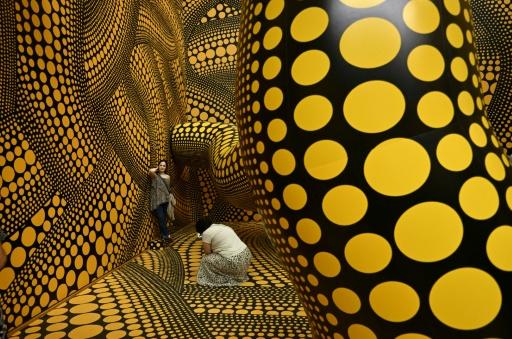 Des visiteurs prennent des photos tandis qu’ils dans l’installation "Infinity Mirrored Room – The Hope of the Polka Dots Buried in Infinity Will Eternally Cover the Universe" lors du dernier jour de l’exposition "Yayoi Kusama" de l’artiste japonaise au musée Ludwig à Cologne, en Allemagne, le 2 août 2026 — Ina FASSBENDER / AFP