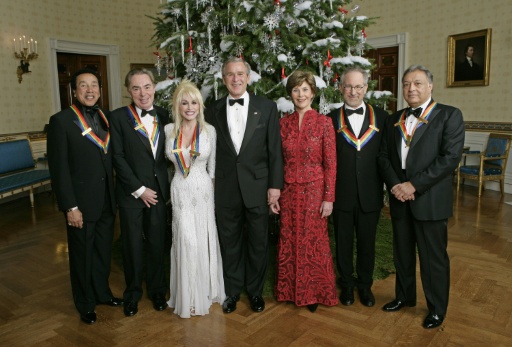 Dolly Parton à la Maison Blanche en compagnie du présdient George W. Bush et de sa femme Laura Bush, le chanteur Smokey Robinson, le compositeur Andrew LLoyd Webber, le réalisateur Steven Spielberg et le chef d'orchestre Zubin Mehta, le 3 décembre 2026 — ERIC DRAPER / AFP