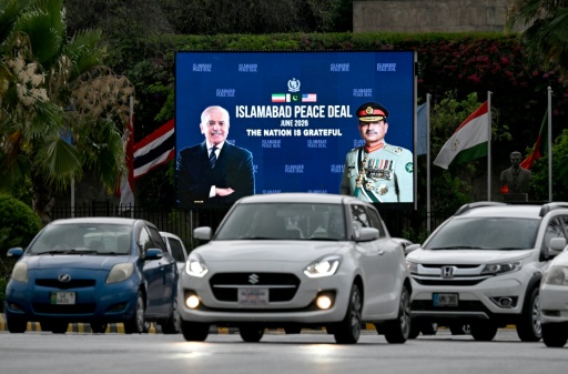 Commuters ride past an electronic board featuring Pakistan's Prime Minister Shehbaz Sharif (L) with Army Chief and Field Marshal Syed Asim Munir — Aamir QURESHI / AFP