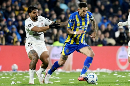 Matheus Bidu, de Corinthians, disputa la pelota con Ángel Di María, de Rosario Central, durante un partido de la Copa Libertadores jugado en Rosario el 13 de agosto de 2026 — Marcelo Manera / AFP