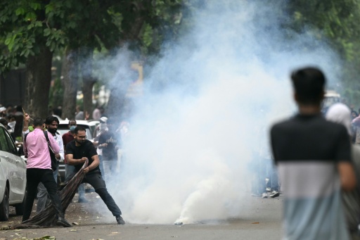 Supporters of the Cockroach Janta Party try to cover a tear gas cannister with cloth during the protest in New Delhi — Sajjad HUSSAIN / AFP