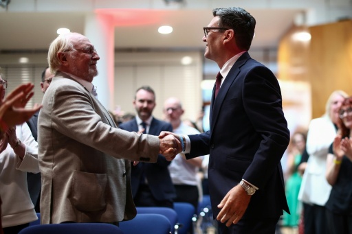Andy Burnham (à droite) serre la main de Neil Kinnock (à gauche), ancien chef du Parti travailliste dans les années 1980 et 1990, à son arrivée, avant d'être confirmé comme nouveau chef du Parti travailliste et prochain Premier ministre du pays, lors du "congrès extraordinaire du Parti travailliste" qui s'est tenu dans le centre de Londres le 17 juillet 2026 — Henry Nicholls / AFP