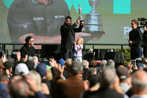 Ryan Fox (C) holds the Open champion's Claret Jug trophy aloft as daughter Isobel looks up with thousands cheering in Auckland — Ben STRANG / AFP