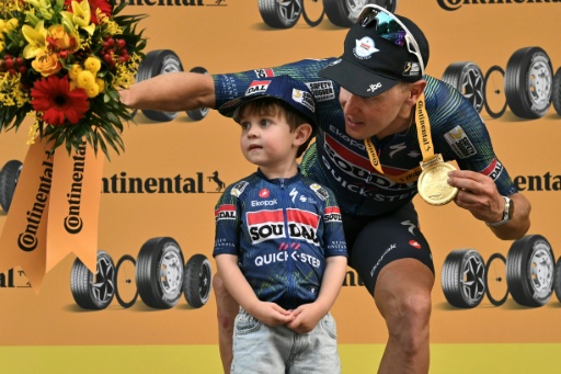 Tim Merlier junto a su hijo Jules en la ceremonia del podio tras ganar la duodécima etapa del Tour de Francia. En Chalon-sur-Saône (centro de Francia), el 16 de julio de 2026 — Jeff PACHOUD / AFP