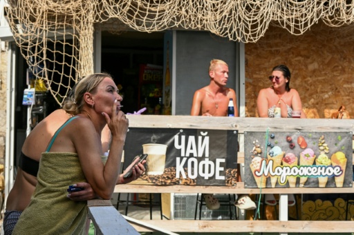 Sur une plage à Simeïz, en Crimée annexée, des touristes attablés à un café, le 21 juillet 2026 — Igor IVANKO / AFP