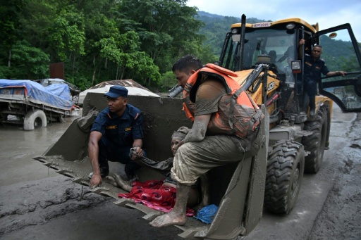 Personal de socorro lleva en la pala de una excavadora a una persona rescatada entre el lodo tras las inundaciones registradas en el distrito de Nuwakot, el 26 de agosto de 2026 en Devghat, en el centro de Nepal — Prakash Mathema / AFP