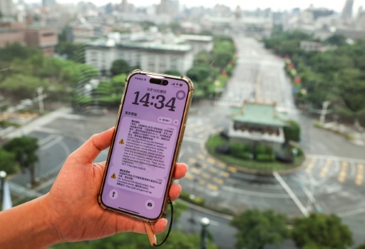 A person holds a mobile phone as streets look empty during an air raid drill in Taipei — I-Hwa Cheng / AFP