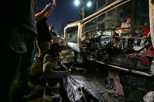Des passants et des secouristes inspectent la carcasse du minibus dans lequel une bombe a explosé, à Jaramana, près de la capitale syrienne, Damas, le 6 août 2026 — LOUAI BESHARA / AFP