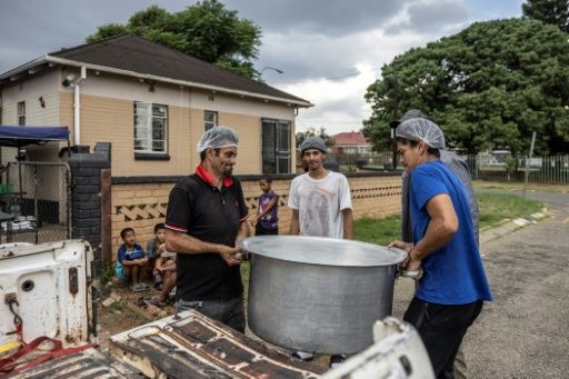 Unos voluntarios de la organización Hunger Has No Religion (HHNR-SA) descargan una olla de comida de un vehículo en Coronationville, cerca de Johannesburgo, el 5 de marzo de 2025 — Roberta Ciuccio / AFP
