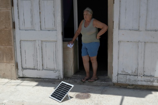A woman stands near a solar panel during a nationwide power outage in Havana, the third since the start of the year