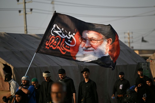 Shiite Muslim pilgrims hold a flag bearing the portrait of Iran's slain supreme leader Ayatollah Ali Khamenei as they march to the Iraqi city of Karbala — Hussein FALEH / AFP