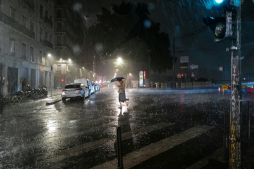 Une passante dans une rue de Lyon pendant un orage, le 16 juillet 2026 — OLIVIER CHASSIGNOLE / AFP