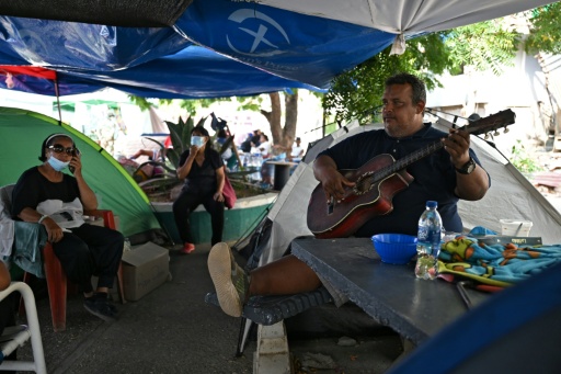 A survivor plays the guitar at a makeshift camp in La Guaira, Venezuela on July 4, 2026, following the June 24 twin earthquakes