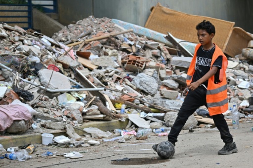 A boy plays football next to rubble in La Guaira, Venezuela