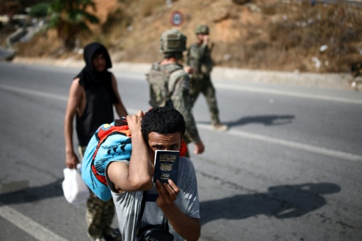 Un candidat à l'émigration montre son passeport yéménite alors qu'il est raccompagné par des militaires jusqu'au poste-frontière entre le Maroc et l'enclave espagnole de Ceuta, le 2 août 2026 — Henry Nicholls / AFP