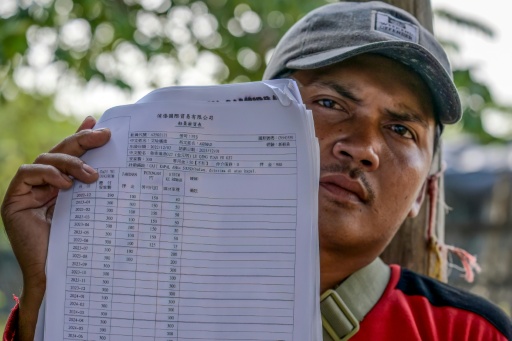 Akhmad, an Indonesian former crew member on a Chinese fishing vessel, shows a document indicating his monthly pay — BAY ISMOYO / AFP