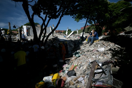 A rescuer sits on the rubble of a collapsed building in Cali, Colombia, which was hit by the strongest quake this century — JOAQUIN SARMIENTO / AFP