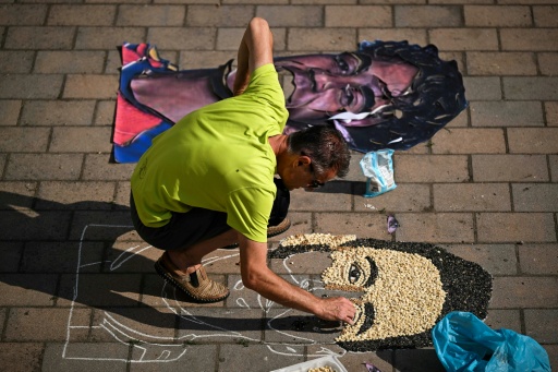 El artista kosovar Alkent Pozhegu compone un mosaico con semillas y granos en el suelo de los delanteros de España Lamine Yamal (izq.) y Argentina Lionel Messi el 16 de julio de 2026 en la localidad de Gjakova — Armend Nimani / AFP