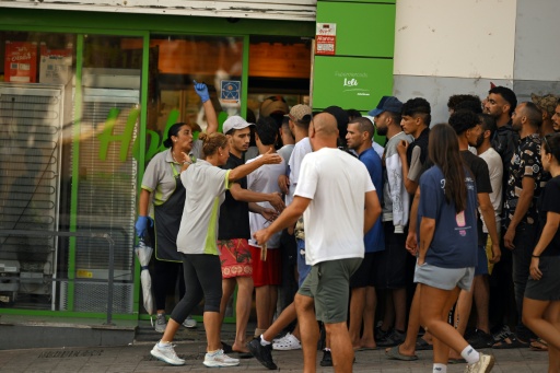 Des employés d'un supermarché (G) tentent de refouler des migrants cherchant à entrer dans le magasin dans l'enclave espagnole de Ceuta, le 1er août 2026 à Ceuta — JORGE GUERRERO / AFP