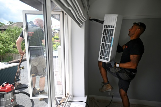 Engineers from Springett Elite Services install an air conditioning unit at a residential home in Croydon, south London, on July 1, 2026. A small but growing proportion of British households is embracing air conditioning (AC) to deal with increasingly hot summers. But the trend has attracted criticism, particularly from sustainability experts who argue it should not be the "default answer".