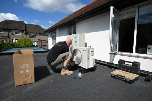 An engineer installs an air conditioning unit on the roof of a residential home in Croydon, south London, on July 1, 2026.
