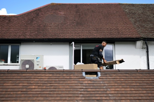 An engineer installs an air conditioning unit on the roof of a residential home in Croydon, south London, on July 1, 2026.