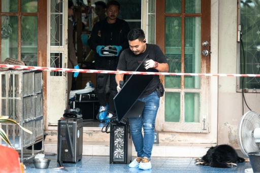 Un enquêteur emporte un ordinateur hors de la maison où un adolescent a tué ses grands-parents avant de perpétrer une fusillade dans une école au nord de Bangkok, la capitale de la Thaïlande (7 août 2026) — Chanakarn LAOSARAKHAM / AFP