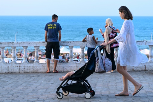 A Tunisian woman looks at her phone as she pushes a pram in La Marsa near Tunis on July 28, 2026. — FETHI BELAID / AFP