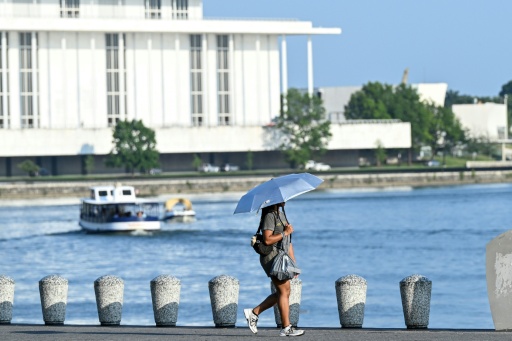 Mulher passeia às margens do rio Potomac, em Washington DC, usando uma sombrinha, em 1º de julho de 2026