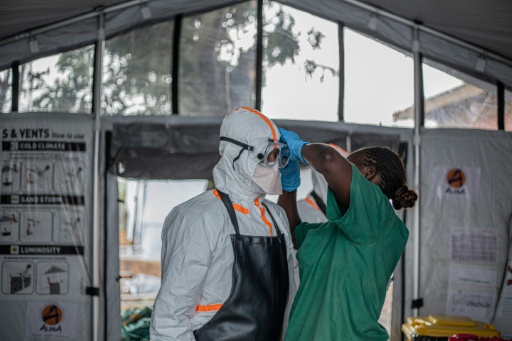 Une soignante aide un médecin à mettre son équipement de protection individuelle (EPI) avant d'entrer dans le centre de traitement Ebola (CTE) de Rwampara pour soigner des patients atteints de la maladie à virus Ebola, le 13 juillet 2026 à Bunia, dans la province de l'Ituri, en RDC