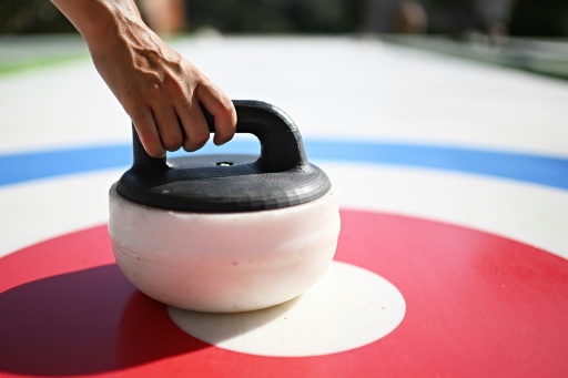 Des personnes s'essaient au curling, un sport d'hiver, sur des pistes synthétiques sans glace installées dans le parc du Colle Oppio, qui surplombe le Colisée, le 24 août 2026 à Rome — Andreas SOLARO / AFP