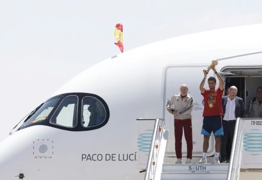 Rodri ergue o troféu da Copa do Mundo no momento em que a porta da aeronave que trouxe a seleção de volta à Espanha se abre, no Aeroporto de Madrid-Barajas, em 20 de julho de 2026, um dia após a conquista do bicampeonato ao derrotar a Argentina na final. — Óscar del Pozo / AFP