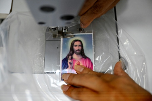 Each roll of body bags bears a prayer card depicting the Sacred Heart of Jesus