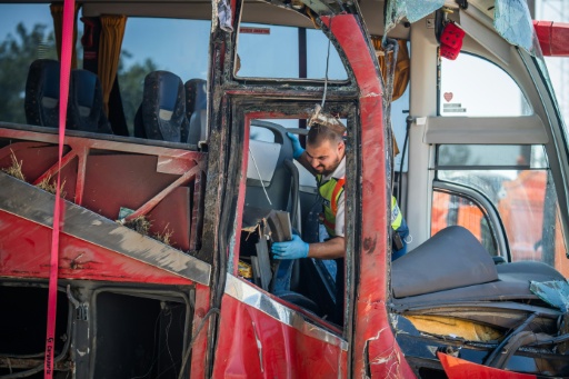 Un policier hongrois inspecte la carcasse du car immatriculé en Pologne qui a quitté la chaussée sur une autoroute hongroise faisant 12 morts et au moins 10 blessés graves, le 16 août 2026 près de Miskolc, dans le nord-est du pays — FERENC ISZA / AFP