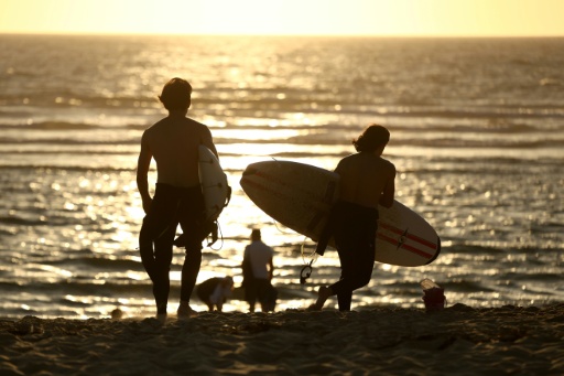 Des surfeurs sur la plage du Porge (Gironde), où quelque 220 personnes se sont retrouvées le 7 août 2026  pour une soirée de solidarité après le mégafeu qui ravagé la commune — ROMAIN PERROCHEAU / AFP