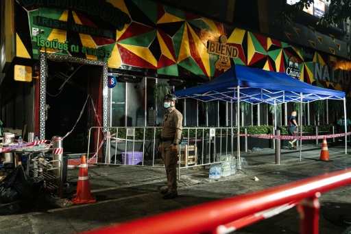 Un policier devant le bar Rong Beer Na Lat Phrao où s'est déclaré un incendie, le 13 juillet 2026 à Bangkok, en Thaïlande