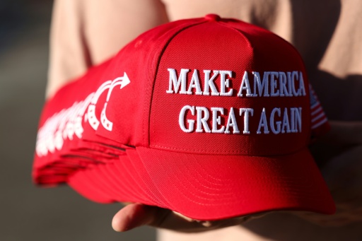 Un membre de Turning Point USA distribue des casquettes "MAGA" aux personnes rassemblées devant un mémorial improvisé en hommage à Charlie Kirk, fondateur de Turning Point USA, devant le siège de l'organisation à Phoenix, en Arizona, le 19 septembre 2025 — CHARLY TRIBALLEAU / AFP