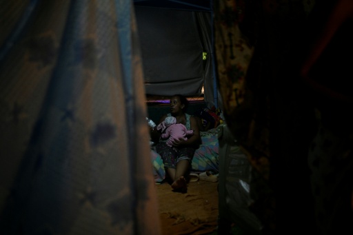 Una desplazada por los terremotos sostiene en brazos a un bebé el 1 de julio de 2026 en un campamento informal en Catia La Mar, en el estado venezolano de La Guaira