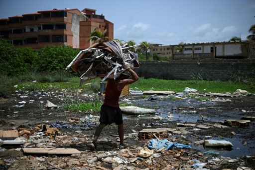 Un hombre se lleva chatarra recuperada de entre los escombros del edificio "La Mar Suite" en Tucacas, Venezuela, el 22 de julio de 2026, casi un mes después del mortal doble terremoto — Federico Parra / AFP