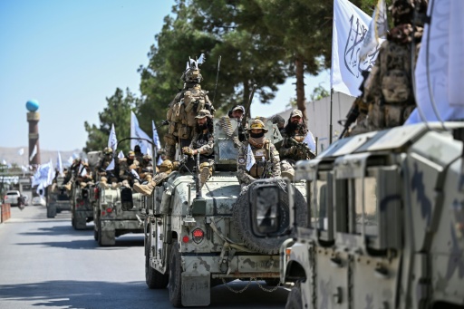 Un convoy de miembros de las fuerzas de seguridad talibanas participa en un desfile frente al antiguo edificio de la embajada de Estados Unidos (al fondo) en Kabul, el 15 de agosto de 2026, mientras celebran el quinto aniversario del regreso al poder del gobierno talibán. — Wakil KOHSAR / AFP