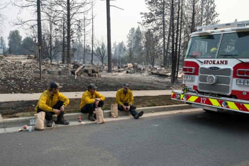 Tres miembros del Departamento de Bomberos de Spokane toman un descanso frente a viviendas residenciales calcinadas en el vecindario de Balboa, en Spokane, Washington, el 2 de agosto de 2026. — Erick Doxey / AFP