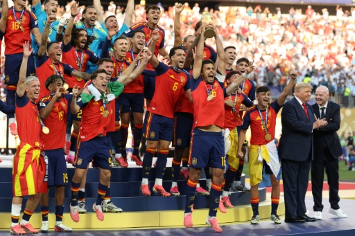 Le milieu de terrain espagnol, Rodri, brandit le trophée de la Coupe du monde aux côtés de ses coéquipiers, encadré par le président américain Donald Trump (2e à droite) et le président de la Fifa Gianni Infantino (à droite), après avoir remporté la finale du Mondial-2026 contre l'Argentine, à East Rutherford, le 19 juillet 2026 — Odd ANDERSEN / AFP