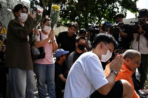 Relatives of victims pray in front of the bar in Bangkok on July 14