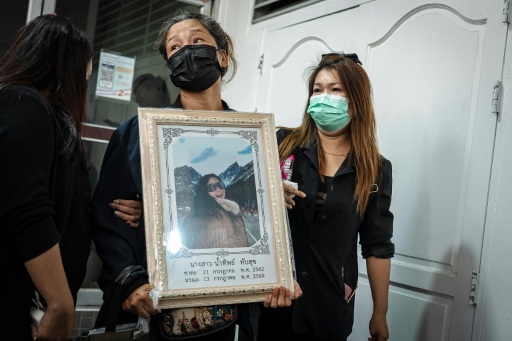 A woman at the Police General Hospital in Bangkok holds a picture of relative killed in the bar fire