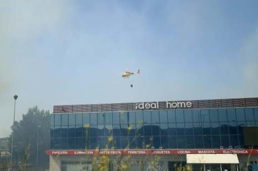 Un helicóptero de los bomberos lanza agua en un área industrial donde se desató el incendio en la localidad española de San Martín de Valdeiglesias, a unos 70 kilómetros al oeste de Madrid, el 26 de julio de 2026 — Óscar del Pozo / AFP