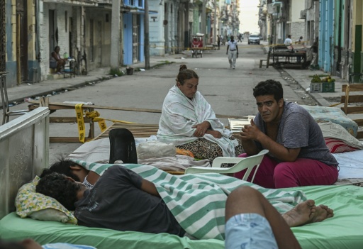 Varias familias pernoctan en camas colocadas en una calle del barrio de Centro Habana tras el derrumbe parcial de su edificio en La Habana, el 30 de julio de 2026. — YAMIL LAGE / AFP