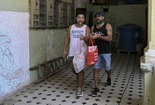 Leandro Wanton (izquierda) y Roberto Ronda caminan para entregar un pedido de su negocio privado de venta de almuerzos en La Habana, el 31 de julio de 2026. — YAMIL LAGE / AFP
